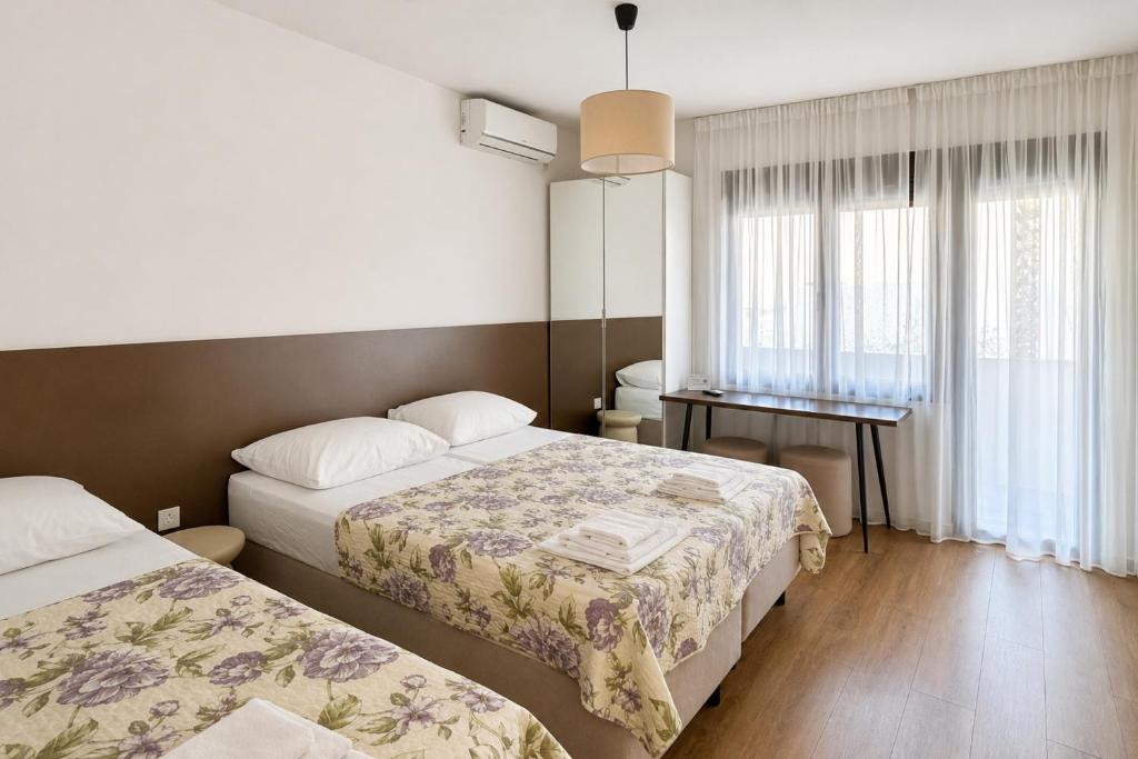 a hotel room with two beds and a desk at Apartments Mara near Split Airport in Kastel Stafilic