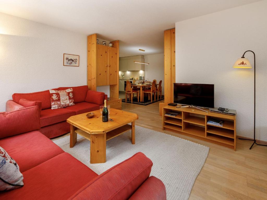 a living room with a red couch and a table at Apartment Terrasse Des Alpes 917 by Interhome in Crans-Montana