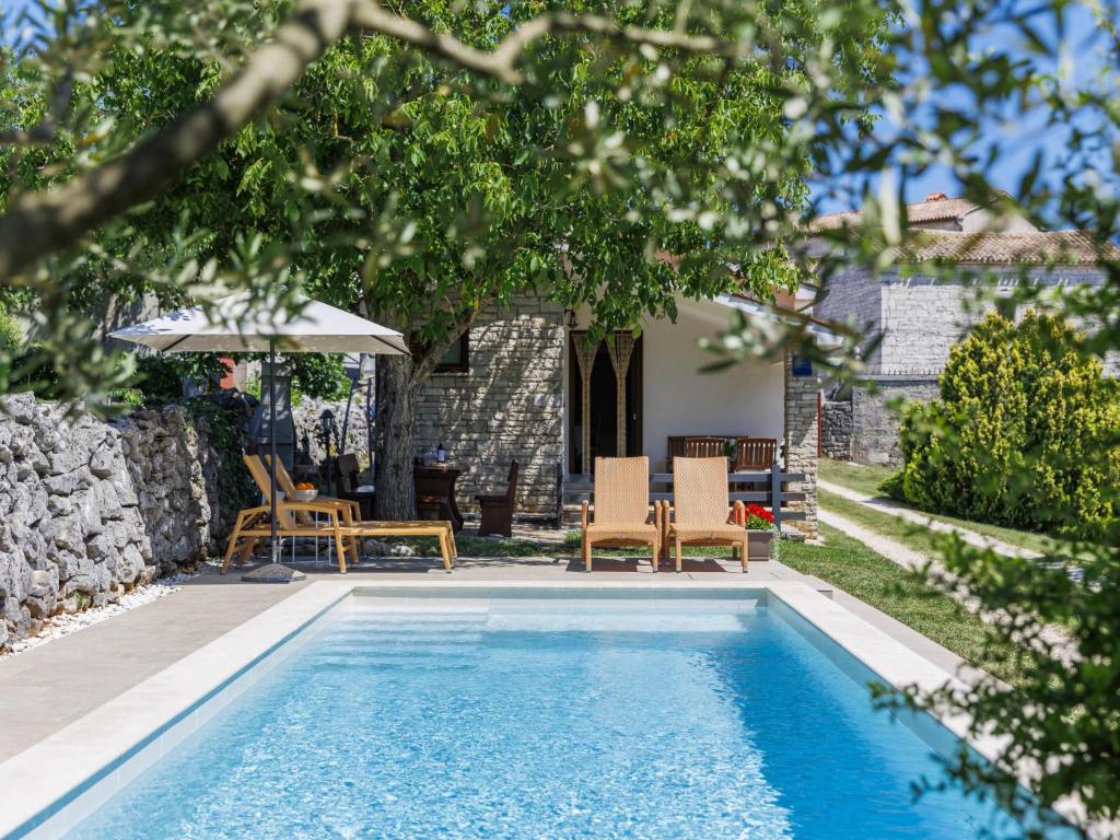 a swimming pool in a yard with chairs and an umbrella at Holiday Home Tomazin by Interhome in Pazin