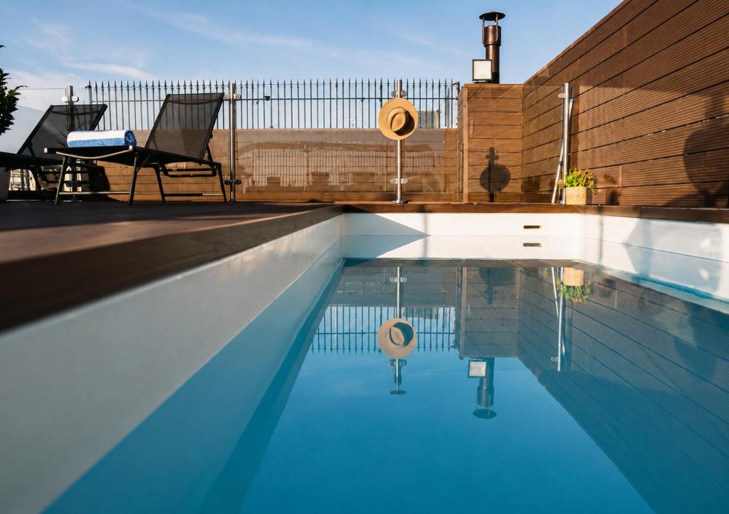 a swimming pool with two chairs sitting next to it at Hotel Casa Gardenia by Blossom Hotels in Barcelona
