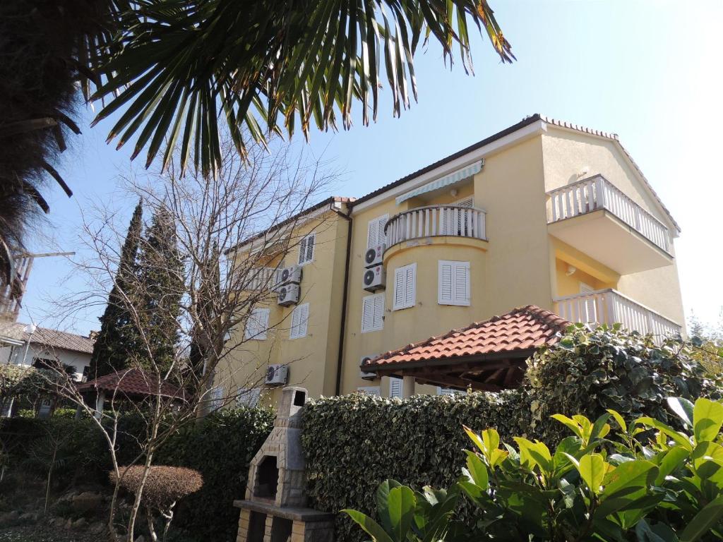 un grand bâtiment jaune avec une clôture devant lui dans l'établissement Apartment Mirela, à Malinska
