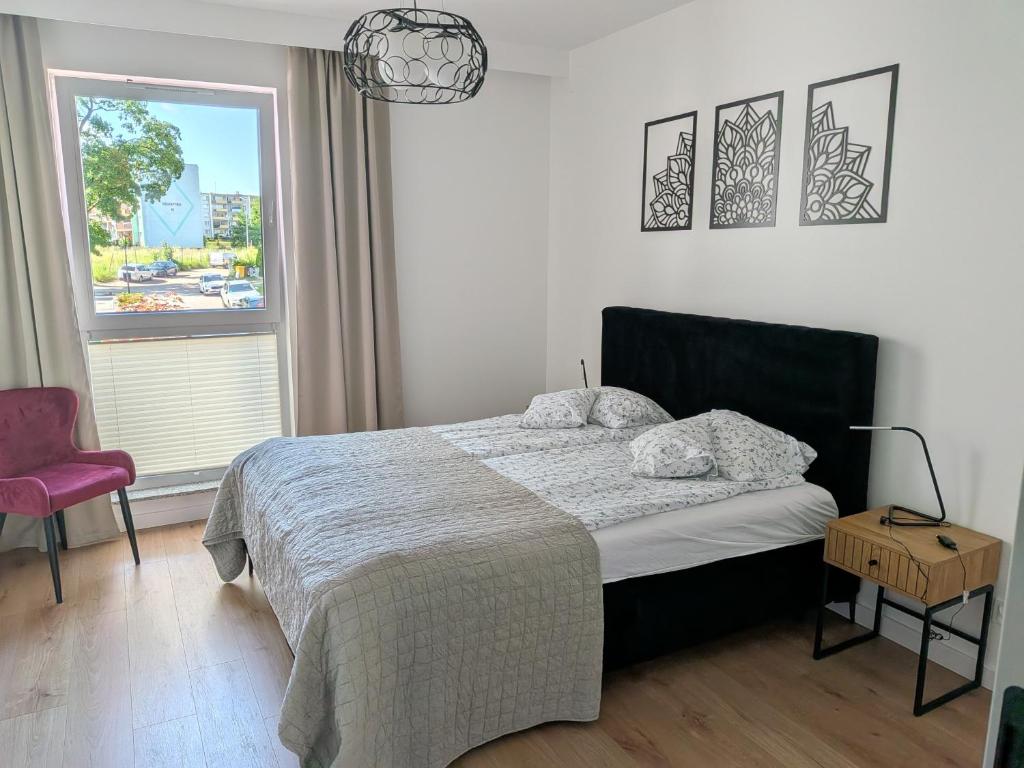 a bedroom with a bed and a chair and a window at Apartament Klonova na Mazurach in Olecko