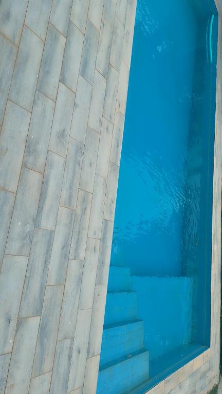 a blue swimming pool with stairs next to the water at Villa Madiba in Somone