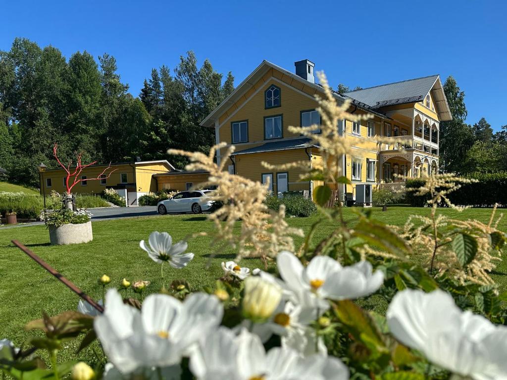 a large yellow house with flowers in the yard at Lokatten Wärdshus in Los
