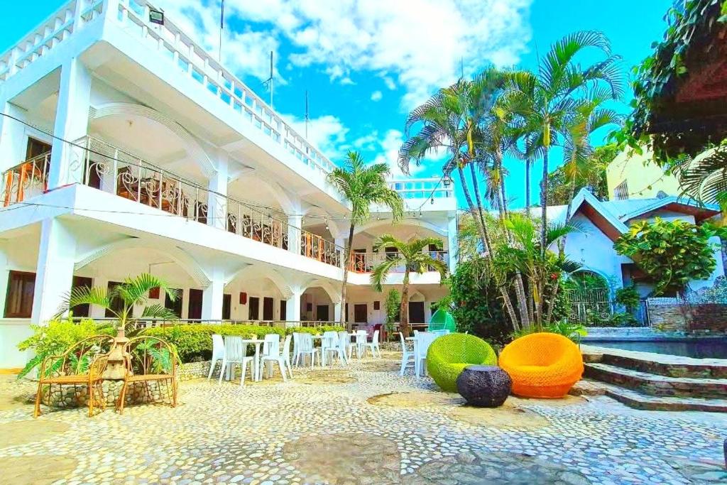 a building with tables and chairs in front of it at Simons Heritage Resort Puerto Galera in Puerto Galera