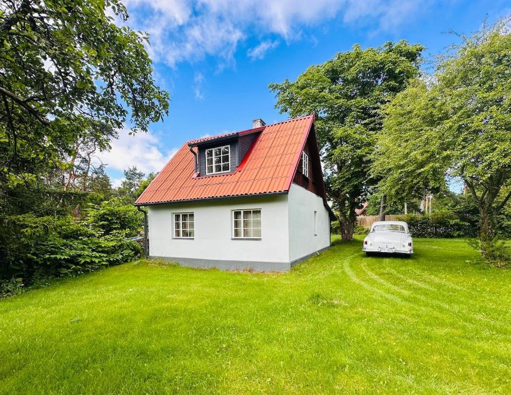 a white house with an orange roof and a white car at Mäeotsa Country House in Laulasmaa