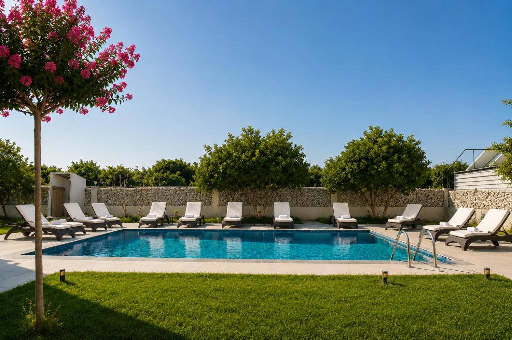 a swimming pool with lounge chairs and a tree at Side Mira Palace & Spa in Side