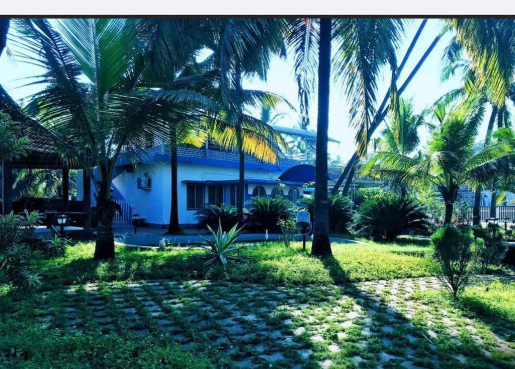 un grupo de palmeras frente a una casa en Silver Sands Malpe Beach Villa, en Udupi