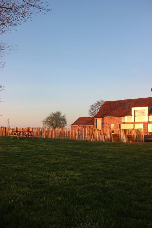 a house in a field next to a fence at Het Plategoed in Oosthoek