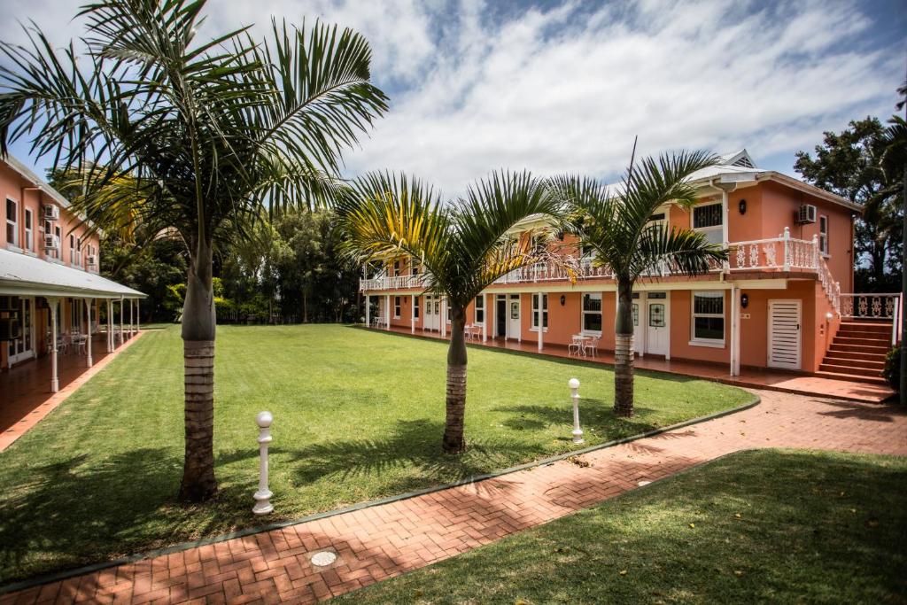 a group of palm trees in front of a house at Sica's Guest House in Durban