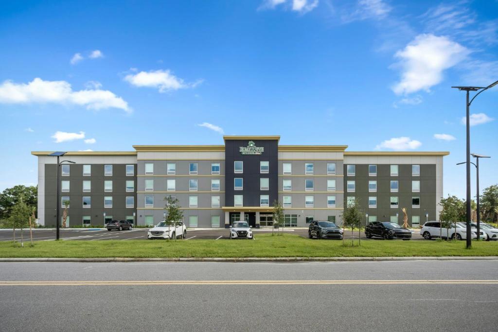 a large building with cars parked in a parking lot at HomeTowne Studios by Red Roof Bradenton in Bradenton