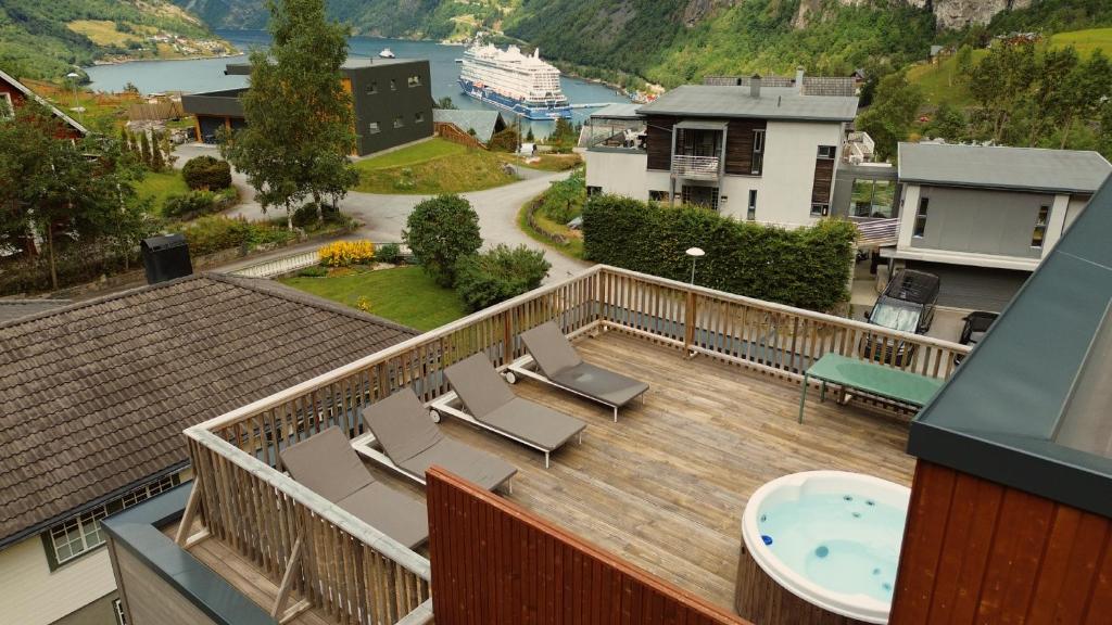a balcony with a hot tub and chairs on a deck at Geirangerbooking in Geiranger