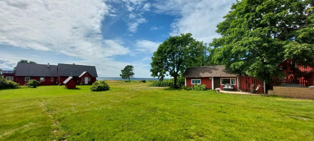 a barn and a house on a grass field at Little Red Sauna by the Sea in Leesi