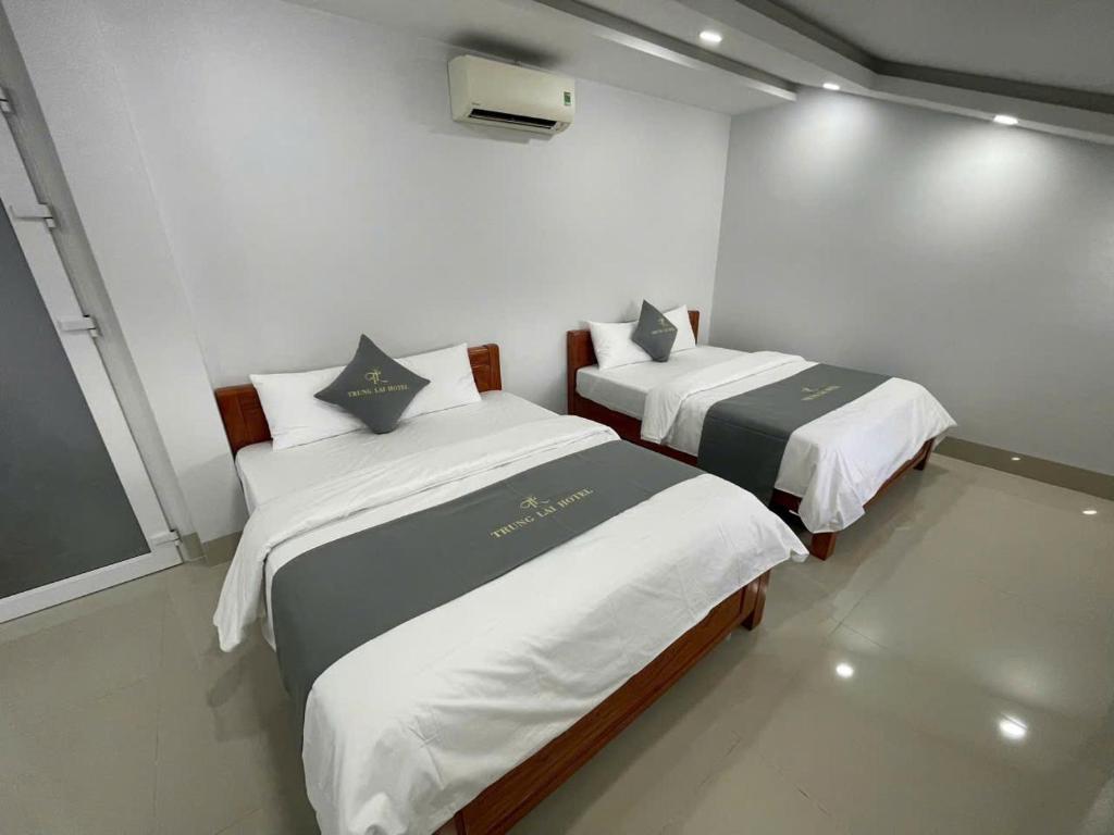 two beds in a room with white walls at TRUNG LÀI HOTEll in Ấp Thái Thương