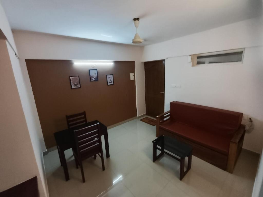 a living room with a couch and a table and chairs at Hovato Brown in Nedumbassery