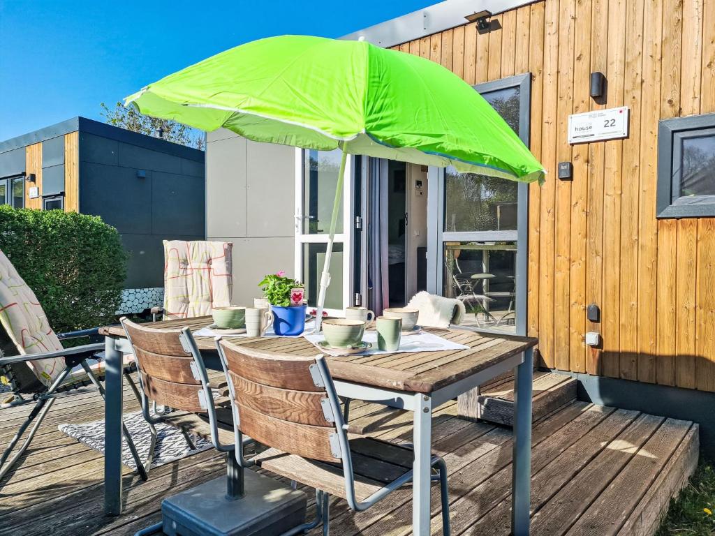 a wooden table with a green umbrella on a deck at Holiday Home Tiny Haus Heidi by Interhome in Beilngries