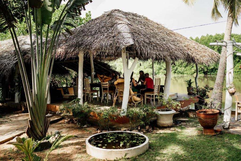 a hut with people sitting at a table under it at Ginger Harmony Tangalle Lagoon View in Tangalle