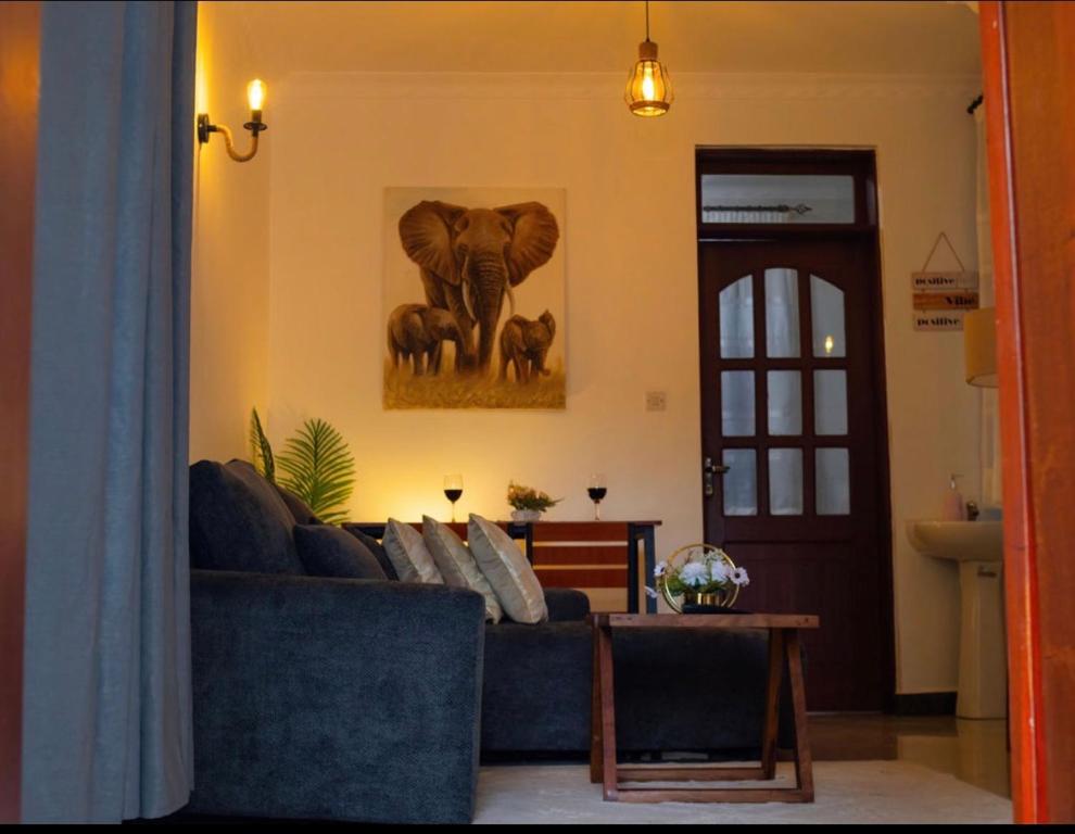 a living room with a blue couch and a picture of an elephant at Lunora Homes in Arusha
