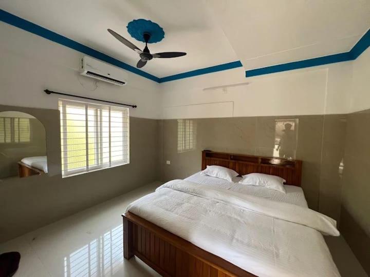 a bedroom with a bed with a ceiling fan at HOLIDAY HOMEs MALPE in Udupi
