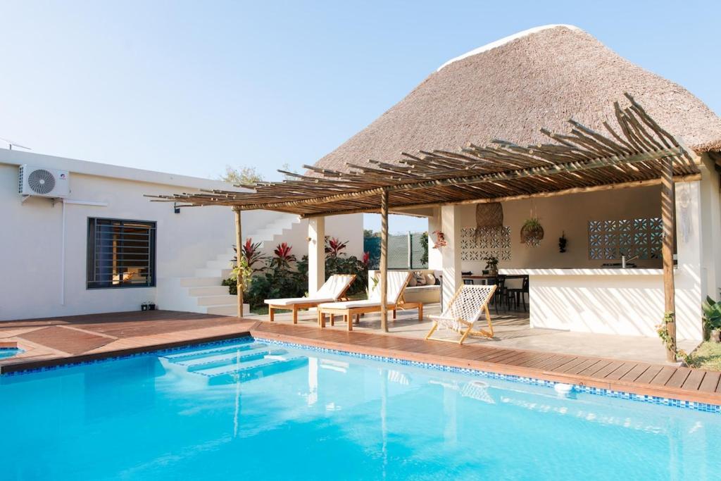 a villa with a swimming pool and a thatch roof at Ka Nicita - Beach house with pool in Praia de Macaneta
