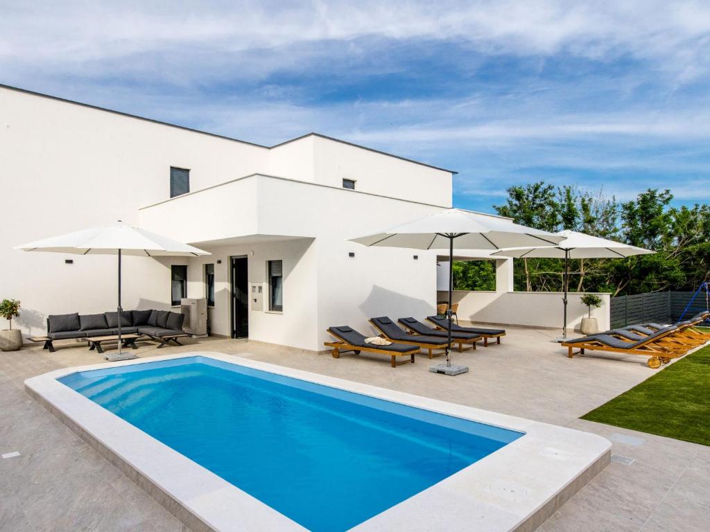 a white house with a swimming pool and umbrellas at Villa Antica by Interhome in Lopar