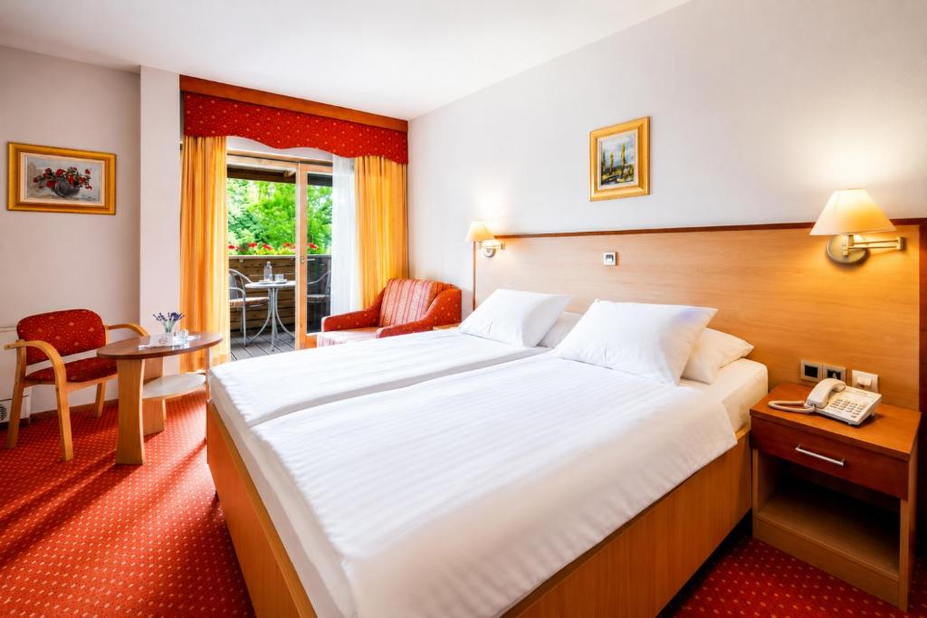 a hotel room with a large bed and a table at Terme Banovci - Hotel Zeleni Gaj in Banovci