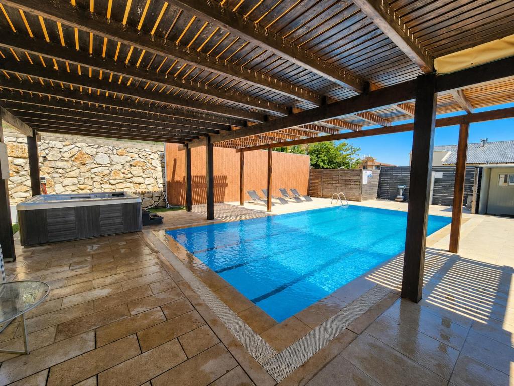 a swimming pool under a wooden pergola at חלום בהר- 2 סוויטות מפנקות עם בריכה ואמבט ספא במתחם in ‘Ein el Asad