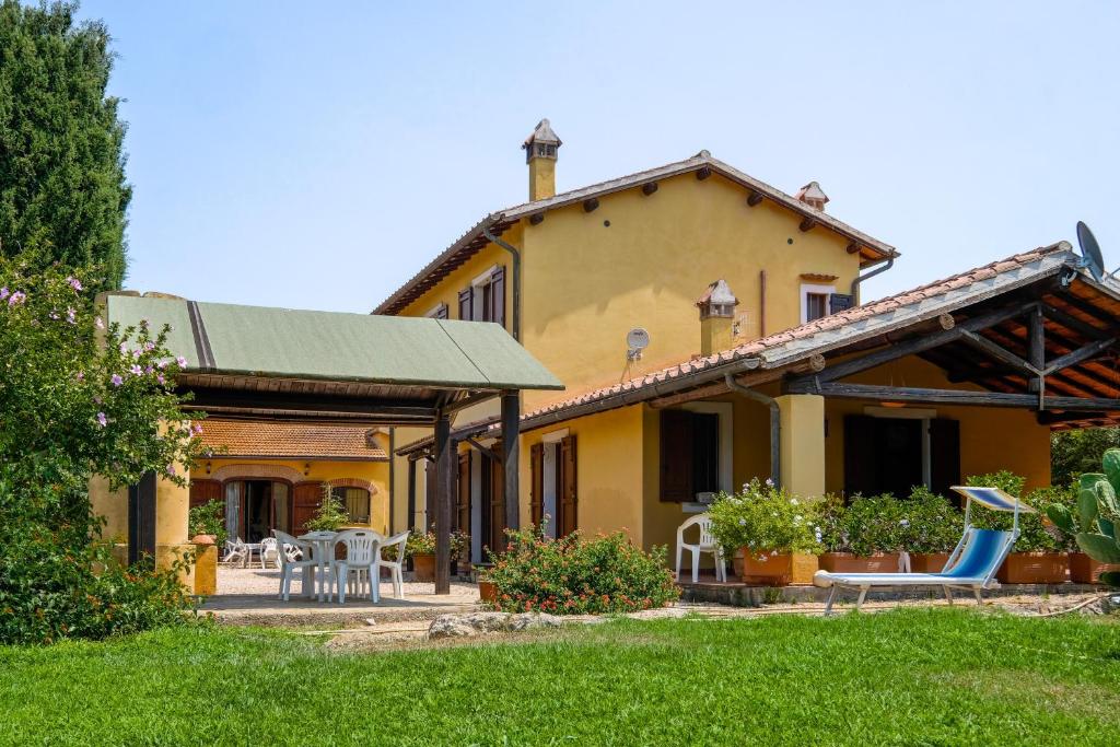 a yellow house with a patio and chairs in the yard at Bed and Breakfast Torrette Etrusche in Capalbio
