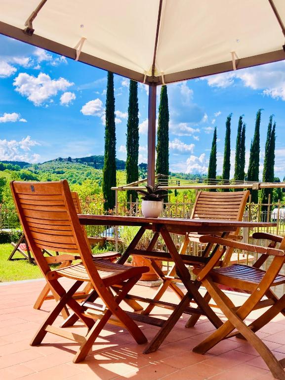 two chairs and a table with an umbrella on a patio at Cipressi Rossi in Greve in Chianti