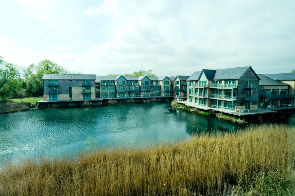 a row of apartment buildings next to a river at De Vere Cotswold Water Park Apartments in Cirencester