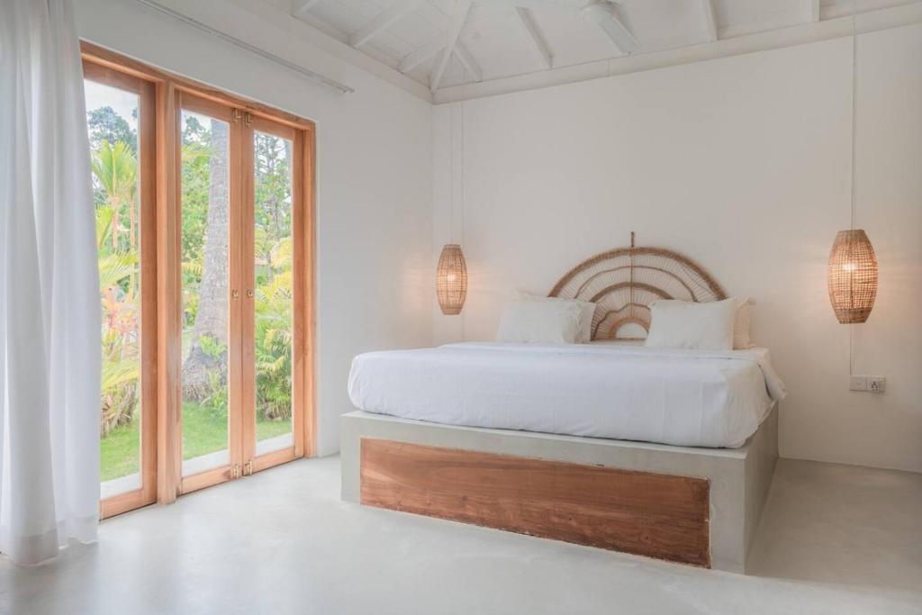 a white bedroom with a bed and large windows at Panta Rei resort in Ahangama
