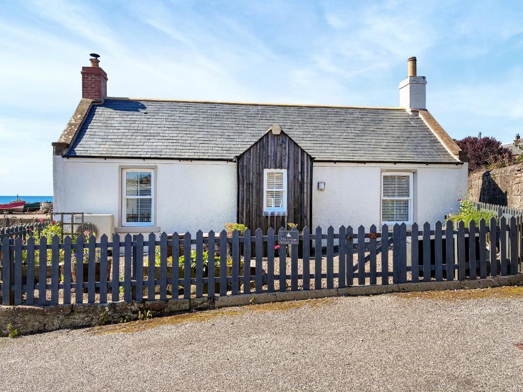 a white house with a fence in front of it at Fifie Cottage in Johnshaven