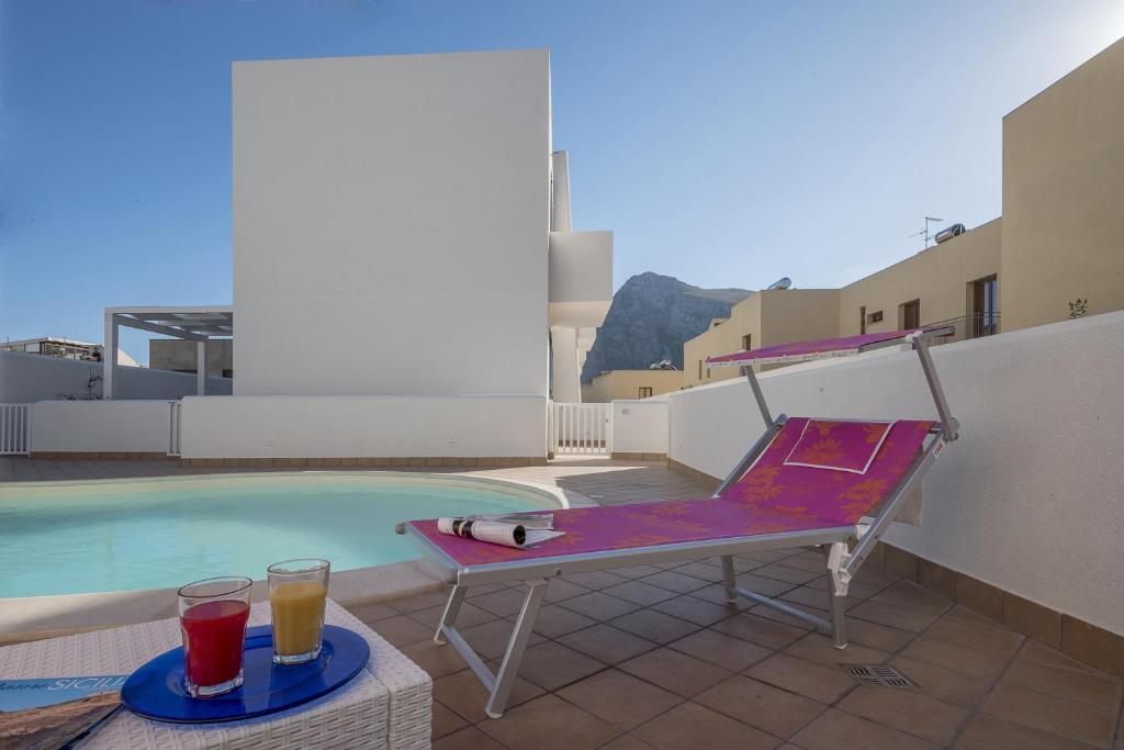 a purple bench next to a swimming pool with two drinks at Blu Mare Apartments in San Vito lo Capo