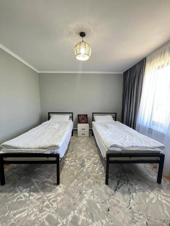 a bedroom with two beds and a chandelier at Kamil Guest House in Shabdan