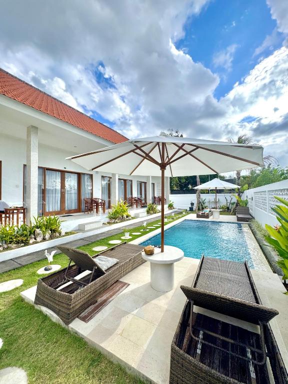 an outdoor patio with an umbrella and a swimming pool at Bayedan Homestay in Badung