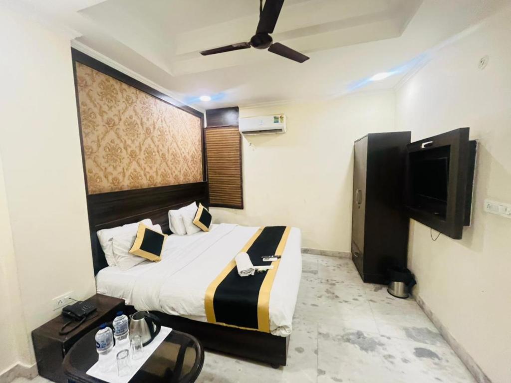 a bedroom with a bed and a flat screen tv at Hotel Dharma Heights - Sector 11 Noida in Noida