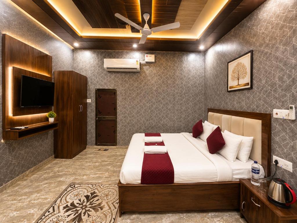a bedroom with a bed with a ceiling fan at Hotel R-A-M-A-N-S-H GRAND INN - Beside Ram Mandir Ayodhya 96,7000,2101 in Ayodhya