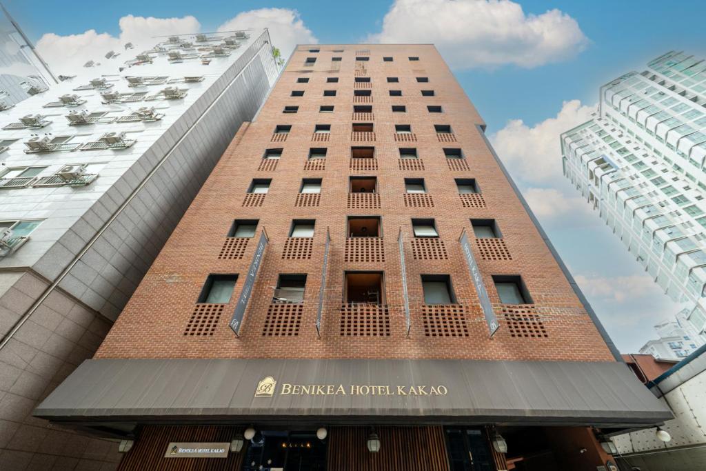 a tall red brick building with a sign on it at Benikea Hotel Kakao in Seoul