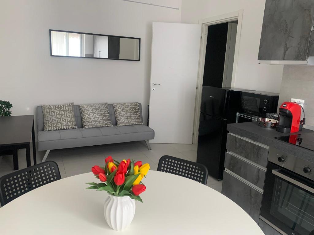 a white table with a vase of flowers on it at Ripalta House in San Donato Milanese