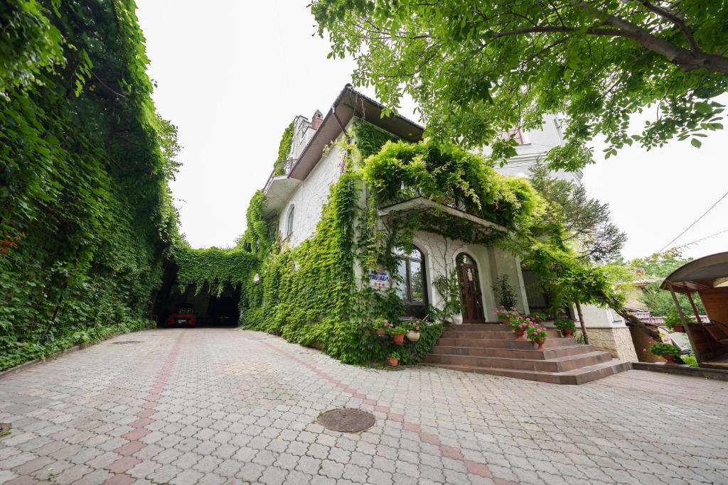 a building covered in green ivy next to a street at Pensiune Taviada in Chişinău