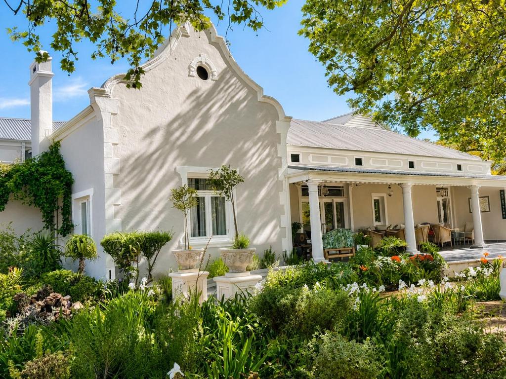 a white house with a garden in front of it at Banhoek Corner Guesthouse in Stellenbosch