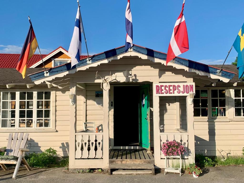 a white building with flags on the roof at Arctic Motel and Kautokeino Camping in Kautokeino