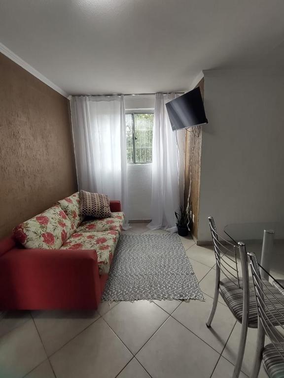 a living room with a red couch and a window at Apartamento térreo bem equipado, fácil acesso in Canoas