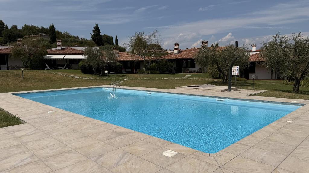a blue swimming pool in front of a house at Harmonia Cottage by Bookinggardalake in Soiano del Lago