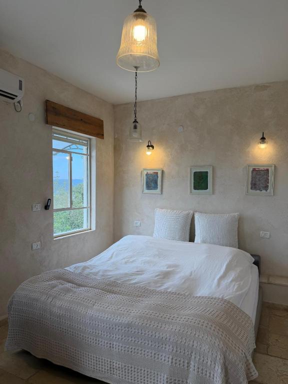 a bedroom with a large white bed with a window at Benichuta in Mitzpe Hila