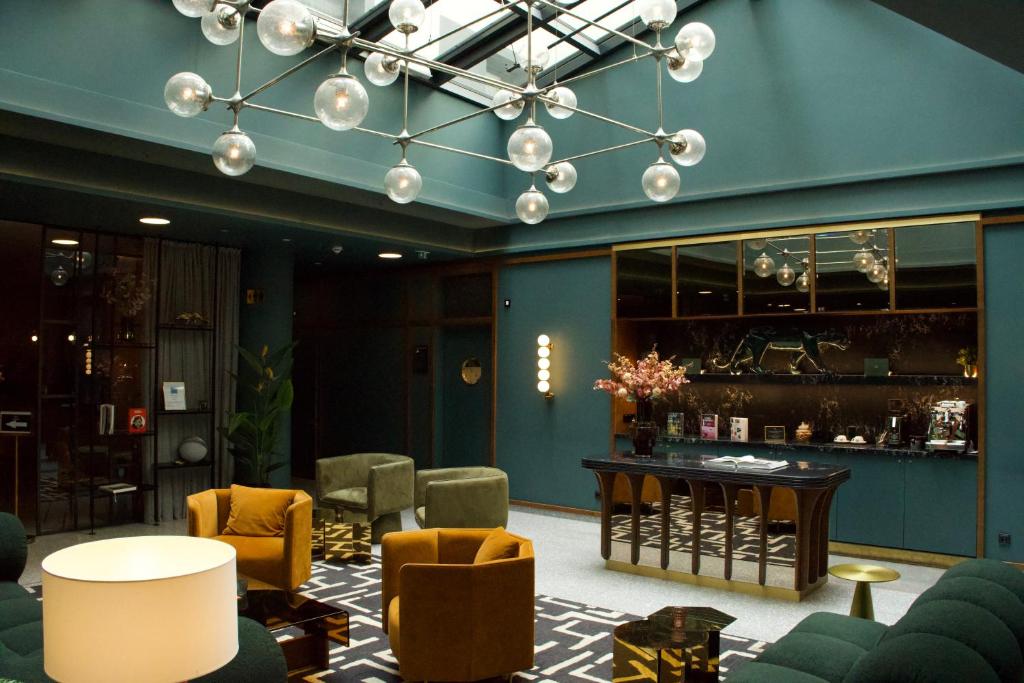 a lobby with a bar with yellow chairs and a blue wall at Hotel MIO by AMANO in Munich