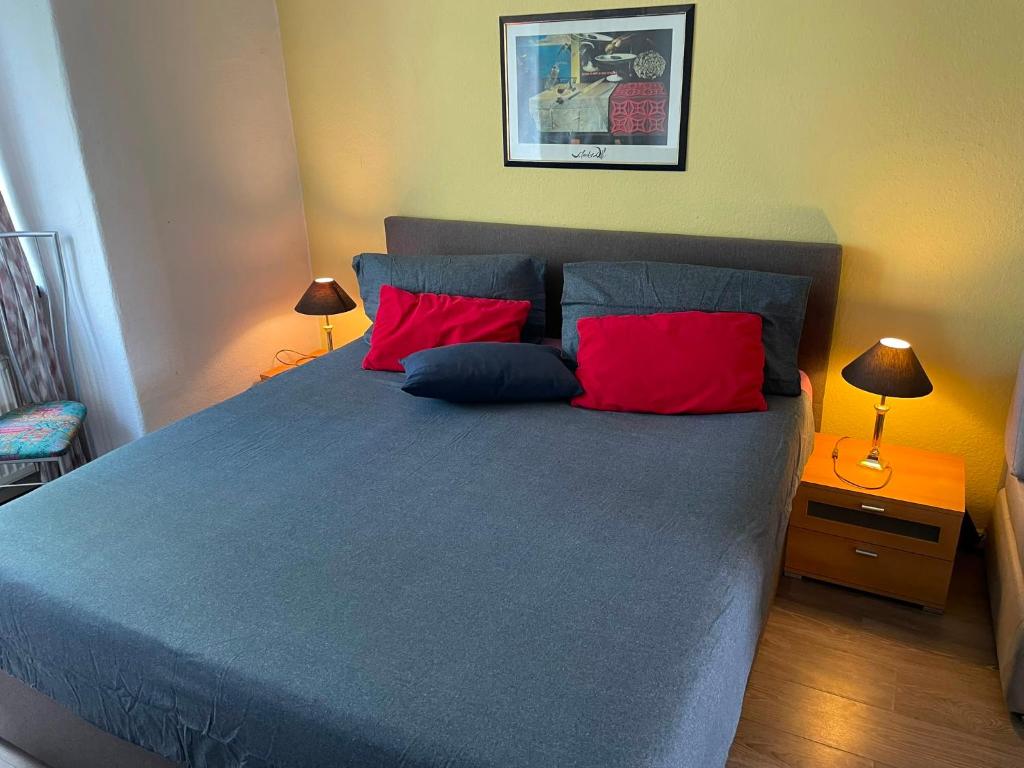 a bedroom with a blue bed with two red pillows at FeWo Möwennest in Warnemünde
