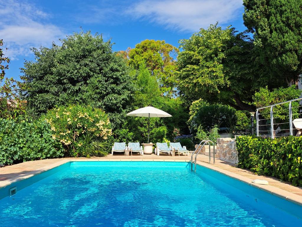 a swimming pool with two chairs and an umbrella at Bed and Breakfast with a View & Pool Bastide de Marie Grasse in Grasse