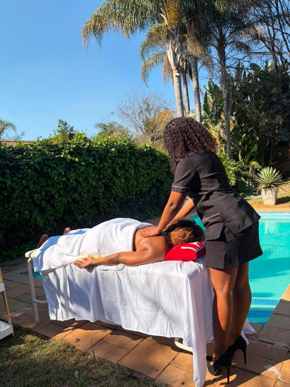 a woman helping a woman on a bed by a pool at Nikkita Wellness Spa in Pretoria