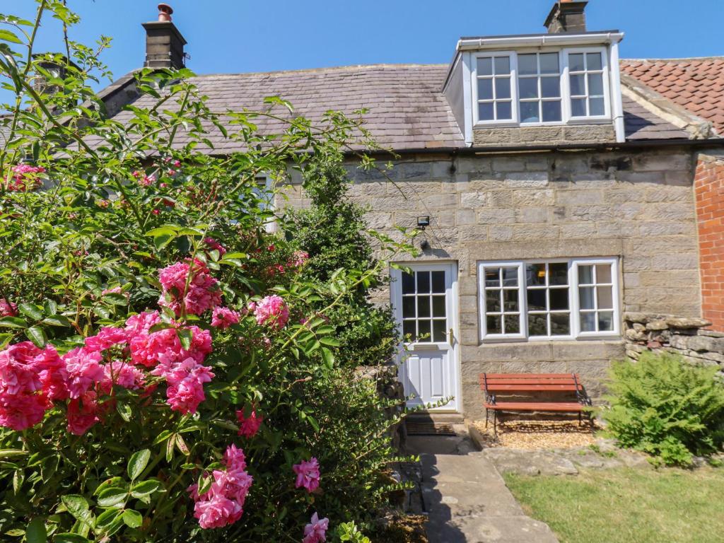 an old stone house with pink flowers and a bench at 4 Lilac Cottages in Whitby
